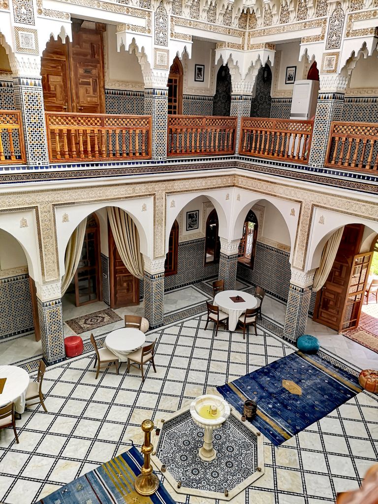 A beautifully decorated Moroccan riad interior showcasing ornate tile work and intricate wooden carvings.