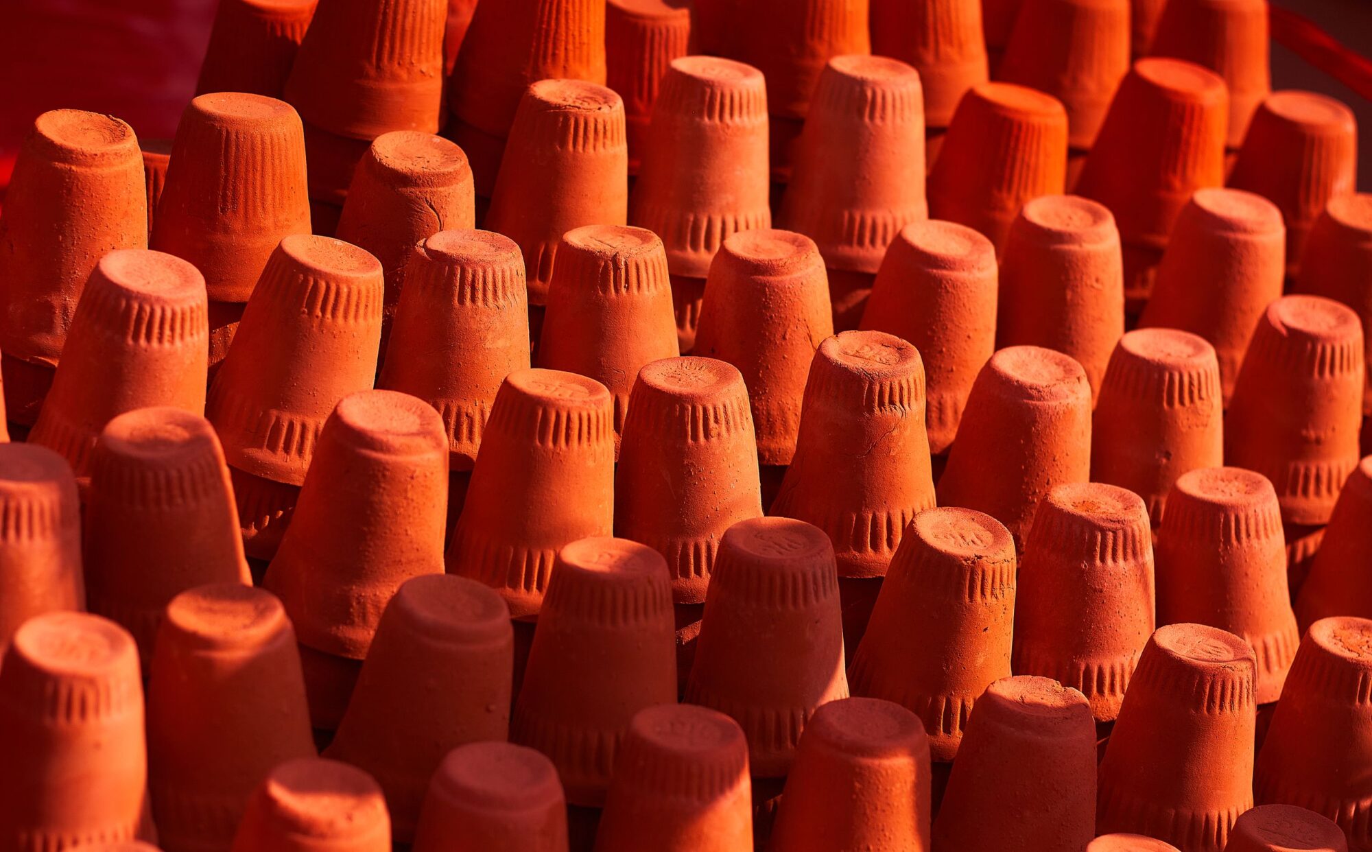 Brightly colored terracotta pots arranged in rows showcasing texture and vibrant colors.