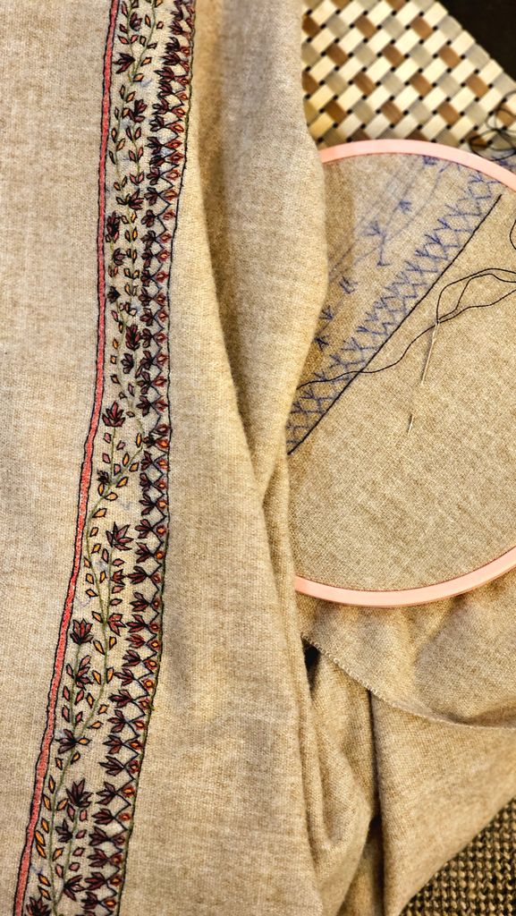 Detailed embroidery work in progress on fabric with hoop and threads.