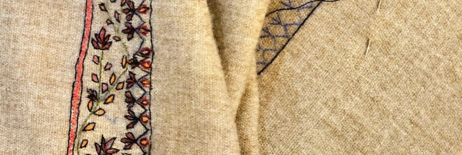 Detailed embroidery work in progress on fabric with hoop and threads.