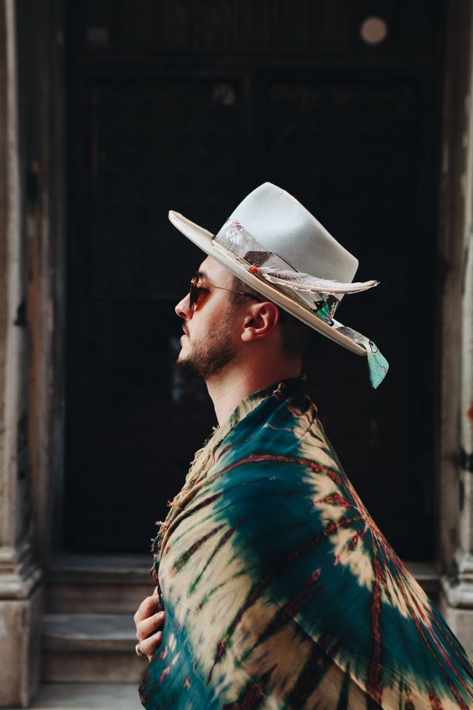 Side profile of a man in a hat and hippie shawl walking on a street in Istanbul.